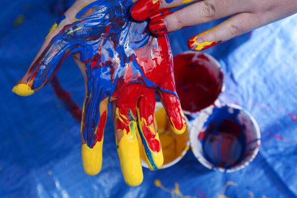 A hand with blue, red and gold paint on it